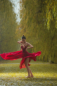 下雨图片摄影照片_穿红色裙子的青年女人在户外跳芭蕾舞