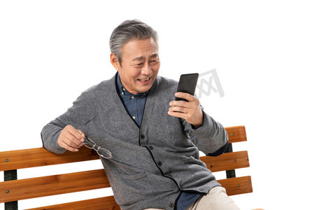 快乐老人坐在长椅上看手机