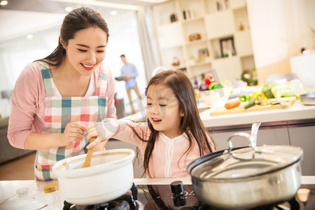 砂锅摄影照片_年轻妈妈和女儿在厨房