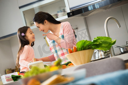 灶台摄影照片_年轻妈妈和女儿在厨房