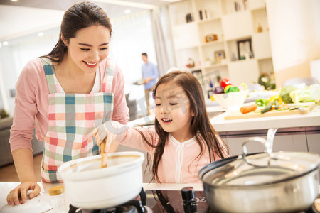 妈妈教孩子做饭摄影照片_年轻妈妈和女儿在厨房