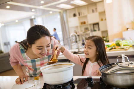 家务劳动摄影照片_年轻妈妈和女儿在厨房