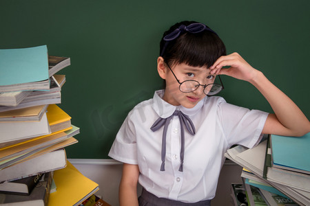 旅游计划摄影照片_坐在书堆里的小学女生