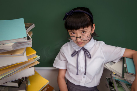 旅游计划摄影照片_坐在书堆里的小学女生