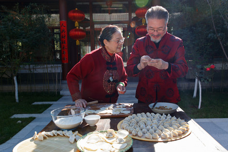 除夕快乐摄影照片_幸福的老年夫妇过年包饺子