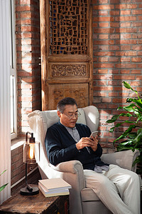 休闲的老年男人坐在沙发上玩手机