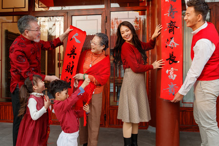 节日庆典摄影照片_幸福的大家庭贴春联庆祝新年