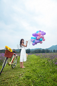 紫色美女摄影照片_青年女人在花海里拿着气球