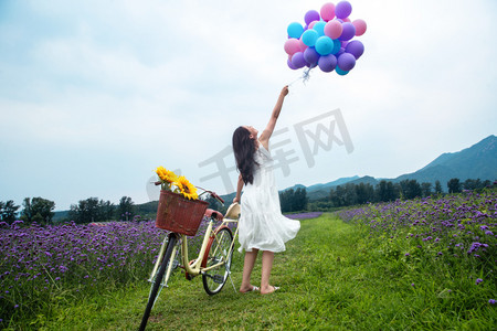 温馨自然摄影照片_青年女人在花海里拿着气球