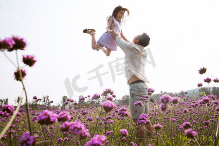 父亲抱着女儿在花丛中玩耍