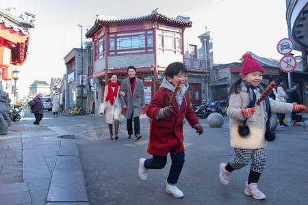 冬天小朋友摄影照片_拿着糖葫芦的小朋友和父母逛街