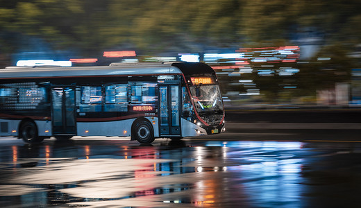 城市马路摄影照片_雨天夜晚行驶的公交汽车摄影图配图