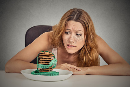 女人渴望糖甜曲奇饼，但担心体重增加