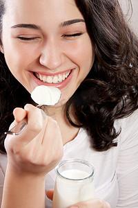吃酸奶摄影照片_快乐的女人与吃酸奶时闭着眼睛在笑