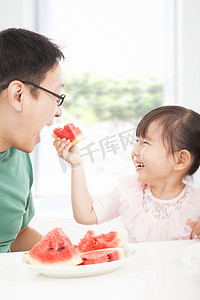 吃女孩西瓜摄影照片_快乐的小女孩与父亲吃水果