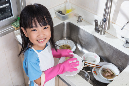亚洲的中国小女孩在厨房里洗盘子