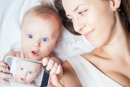 Funny baby girl with mom make selfie on mobile phone