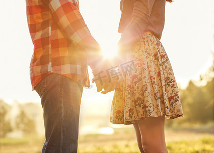 对年轻夫妇在爱在秋天公园牵手散步