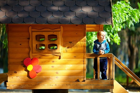 可爱的小男孩在阳光明媚的树屋玩户外