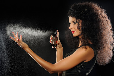 一个美丽的女子，在黑色背景上喷洒香水的一幅肖像