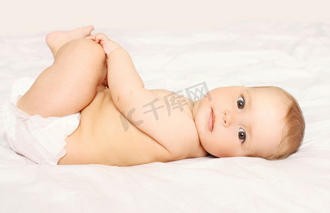 可爱的小宝宝尿布在家里的床上躺着的肖像
