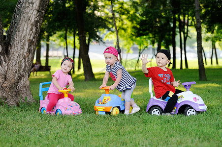 little boy and two little girls driving toy cars