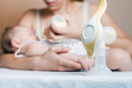 孕婴摄影照片_手动吸奶器和喂养刚出生的婴儿的母亲
