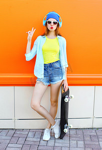 时尚很酷的女孩与滑板听音乐超过c