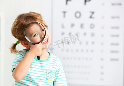 视力测试的概念。儿童女孩用放大镜