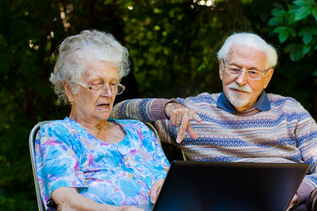 laptop摄影照片_Elderly couple having fun with the laptop outdoors