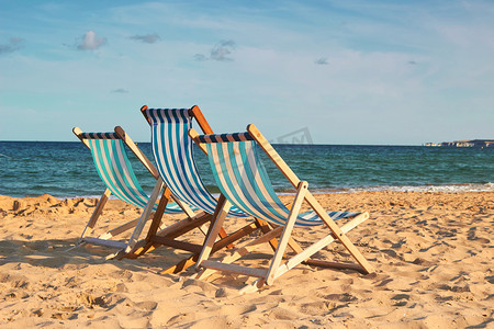 沙滩日光浴摄影照片_三个沙滩椅在金色的沙滩上 