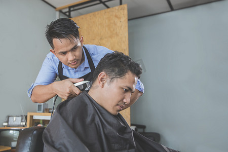 理发店理发摄影照片_理发师在理发店理发的有魅力的男人