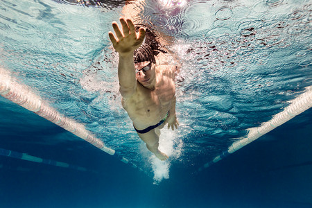 泳池游泳镜中年轻游泳运动员的水下图片