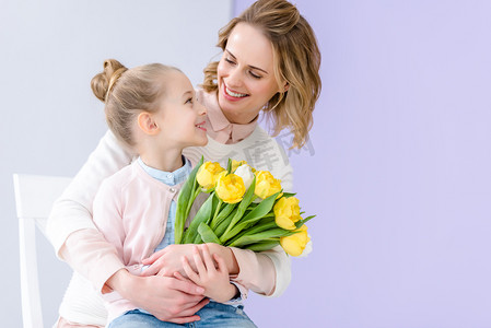 可爱的孩子拥抱母亲与郁金香花束在3月8日