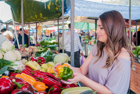 高兴的女人选择绿色和红辣椒粉在超市购物。女人在绿色市场选择生物食品水果辣椒青椒