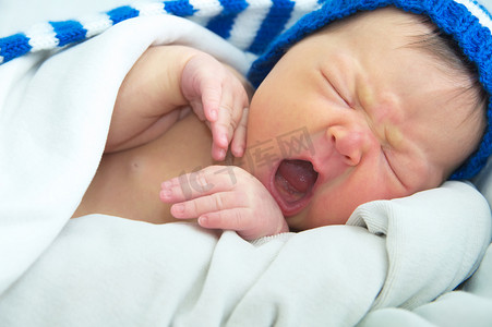 有趣的婴儿脸上戴着帽子，新生儿黄疸婴儿保健概念的白色毯子上