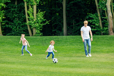 父亲与孩子们在公园里的踢足球