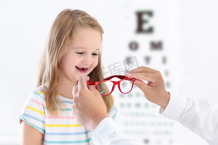 儿童视力测试.小孩子在眼镜店选眼镜。学生的视力测量。给孩子们戴眼罩医生正在做眼科检查。戴眼镜的女孩在字母图上.