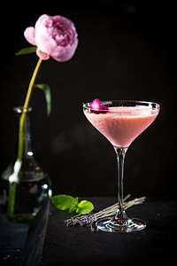 粉色酒精鸡尾酒装饰玫瑰和薄荷特写黑色背景与复制空间。酒吧菜单用粉红色饮料