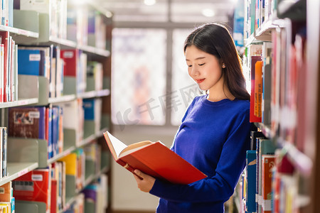亚洲青年学生身着休闲服，在大学图书馆的书架上看书，或以各种书本背景，回到学校概念