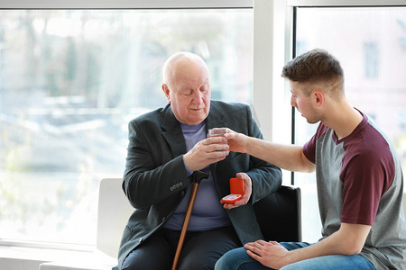 男性照顾者在疗养院给老人服用药片