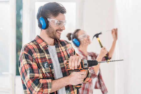 快乐的年轻人在房屋维修过程中使用电钻