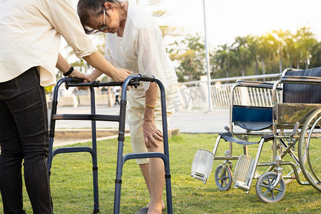 年长的亚洲女性病人在康复过程中，用手触摸膝盖，关节受伤，骨头问题，膝盖疼痛，走路时使用步行机，老年妇女患有骨质疏松症、痛风、佝偻病
