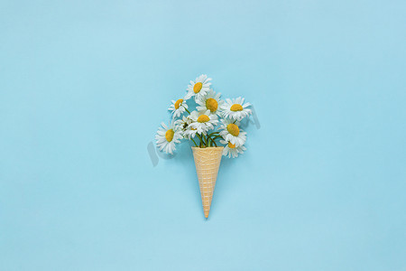 花束甘菊雏菊花华夫饼冰淇淋圆锥上柔和的蓝色彩色纸背景复制空间模板明信片，文字，文本或您的设计平铺顶视图概念你好夏天