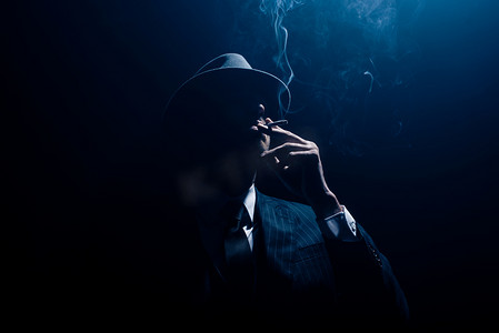 黑道黑道西服的轮廓和在深蓝色背景下抽烟的感觉