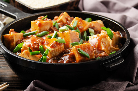 国产的摄影照片_麻婆豆腐在铁锅中，配以猪肉切碎、酱油、西川胡椒大蒜和调味品