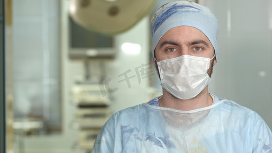 经验丰富的年轻外科医生, 严肃的人戴口罩看着相机