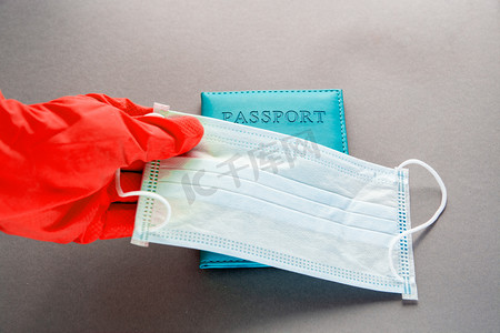  护照藏在面罩、温度计、戴胶乳手套的手后面。验尸官大流行期间新的飞行规则在国外旅行概念