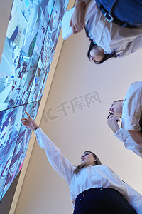 工作内容摄影照片_在数据系统控制室工作的一组女性安全操作员技术操作员在有多个显示器的工作站工作，保安人员在监视室操作多个监视器，监测cctv并讨论