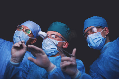 在手术室工作的一组外科医生用蓝色调.执行业务的医疗小组